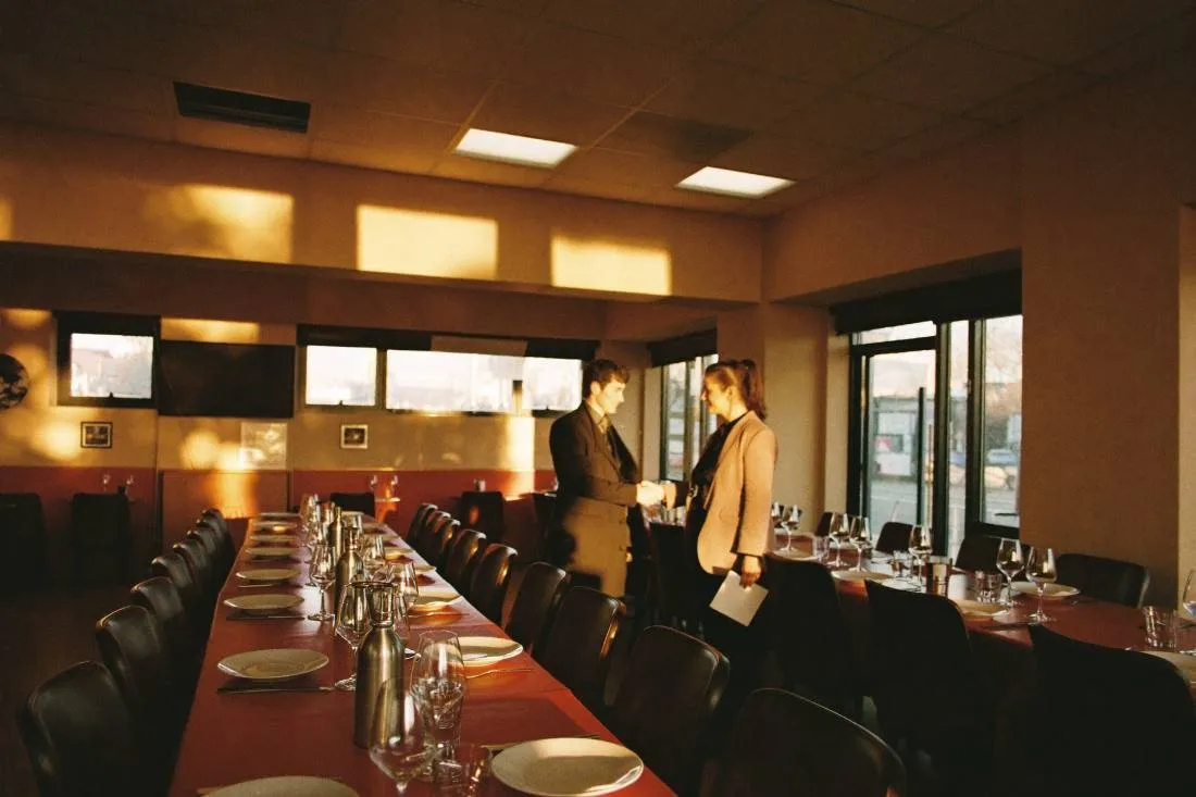 Ein Restaurantinhaber schüttelt einem Partner vor der Öffnung im leeren Gastraum die Hand